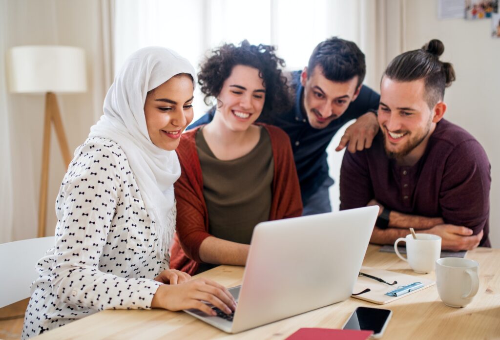 A multi-ethnic group of young friends with laptop indoors, house sharing concept