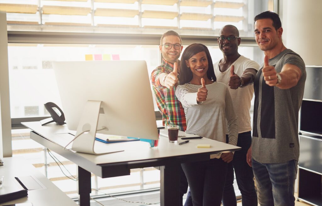 Cheerful office team standing with thumbs up