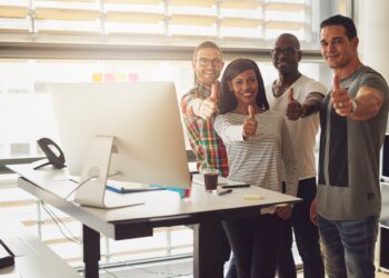 Cheerful office team standing with thumbs up