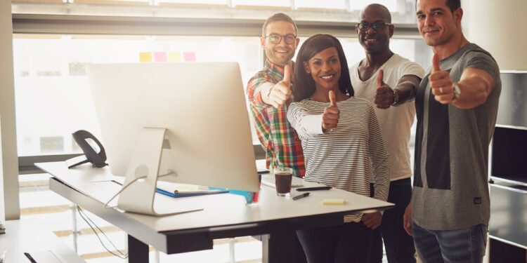 Cheerful office team standing with thumbs up