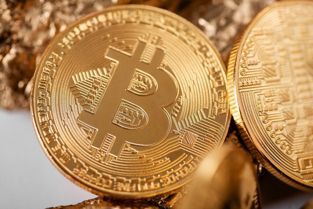 Closeup of golden bitcoin as main cryptocurrency with gold lumps being blurred on background