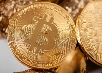 Closeup of golden bitcoin as main cryptocurrency with gold lumps being blurred on background