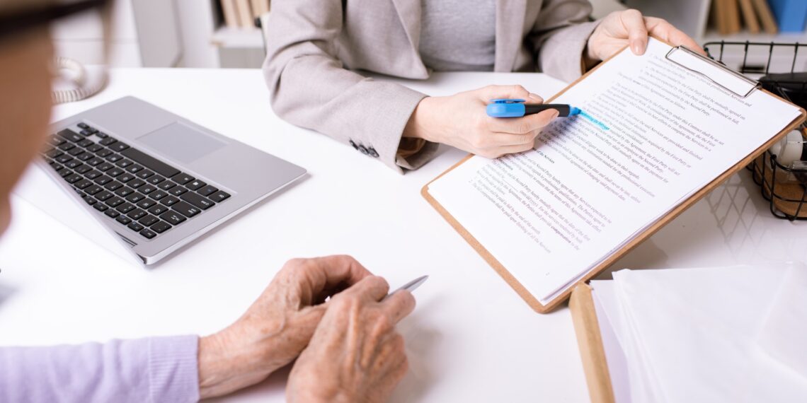 Hands of insurance agent underlining important phrase in document