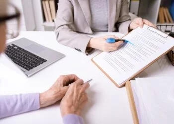 Hands of insurance agent underlining important phrase in document