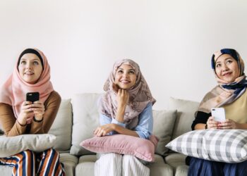Islamic women friends using smart phone and looking up