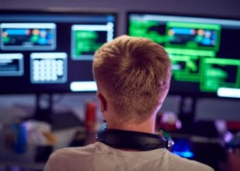 Male Teenage Hacker Sitting In Front Of Computer Screens Bypassing Cyber Security