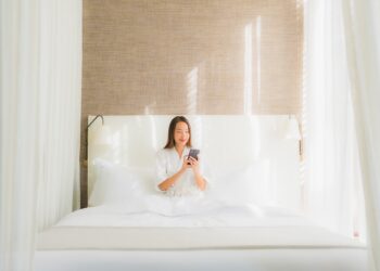 Portrait beautiful young asian woman using smart mobile phone on bed in bedroom