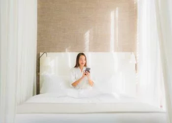 Portrait beautiful young asian woman using smart mobile phone on bed in bedroom