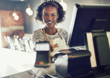 Smiling young bistro waitress holding an electronic card payment machine