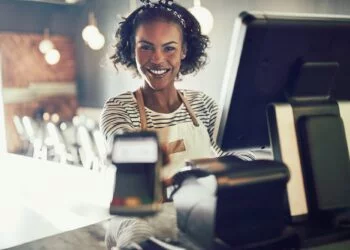 Smiling young bistro waitress holding an electronic card payment machine