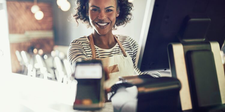 Smiling young bistro waitress holding an electronic card payment machine