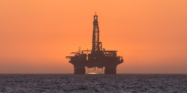Sun setting behind oil drilling platform at Longbeach in Namibia