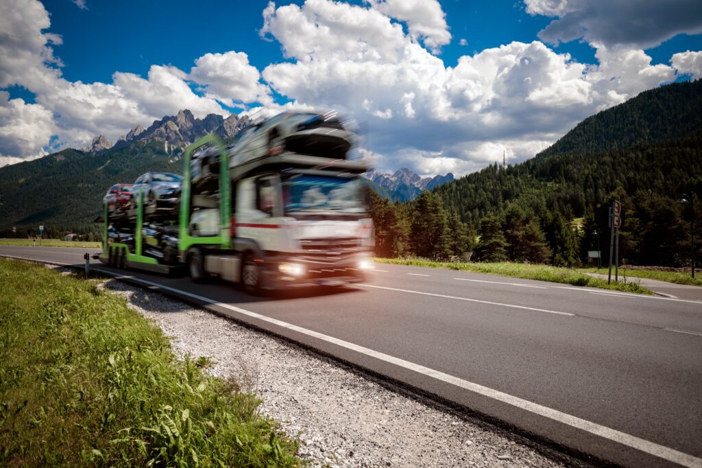 Truck trailer transports new cars rides on highway