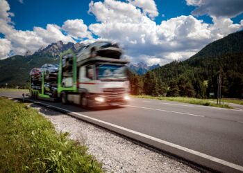Truck trailer transports new cars rides on highway