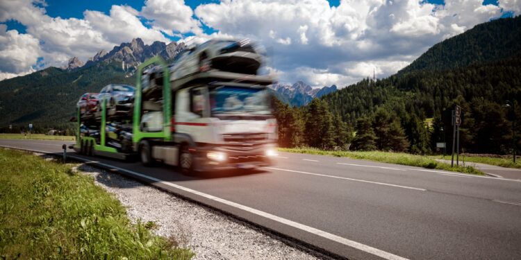 Truck trailer transports new cars rides on highway