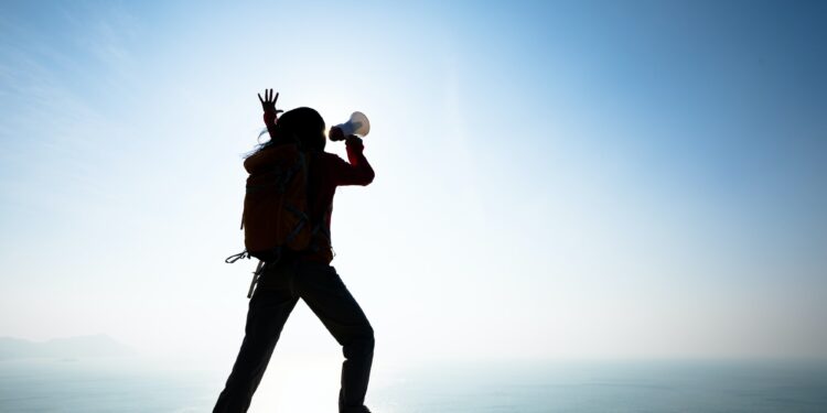 Woman shouting with loudspeaker on sunrise seaside