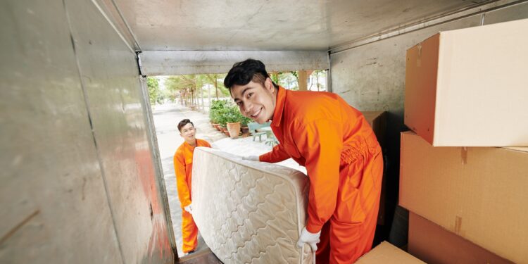 Workers loading mattress in truck