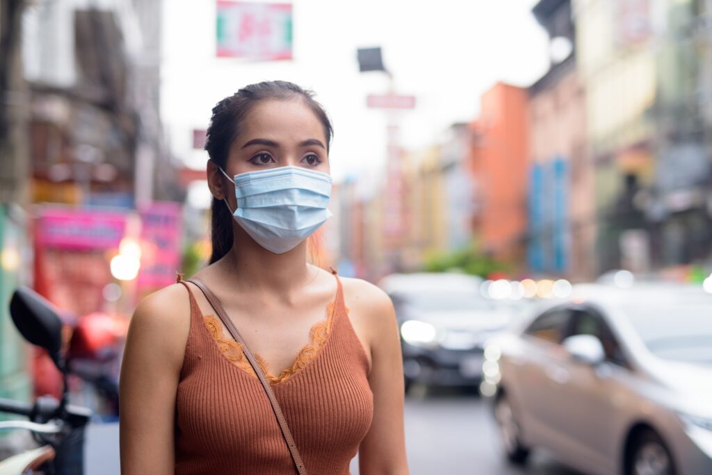 Young Asian tourist woman thinking with mask for protection from corona virus outbreak and pollution