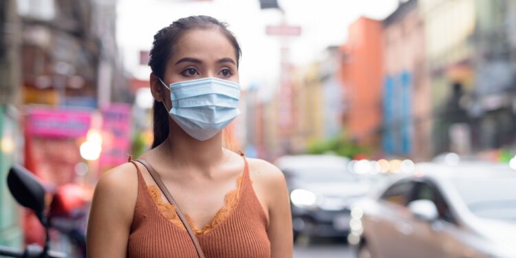 Young Asian tourist woman thinking with mask for protection from corona virus outbreak and pollution