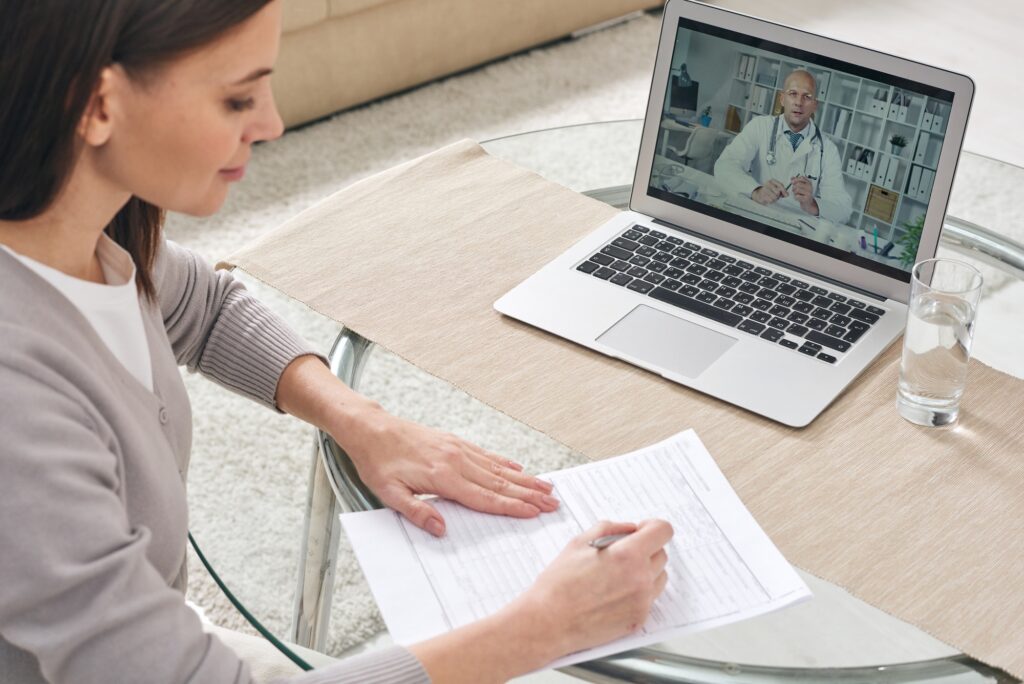 Young woman filling in health insurance form and watching online video