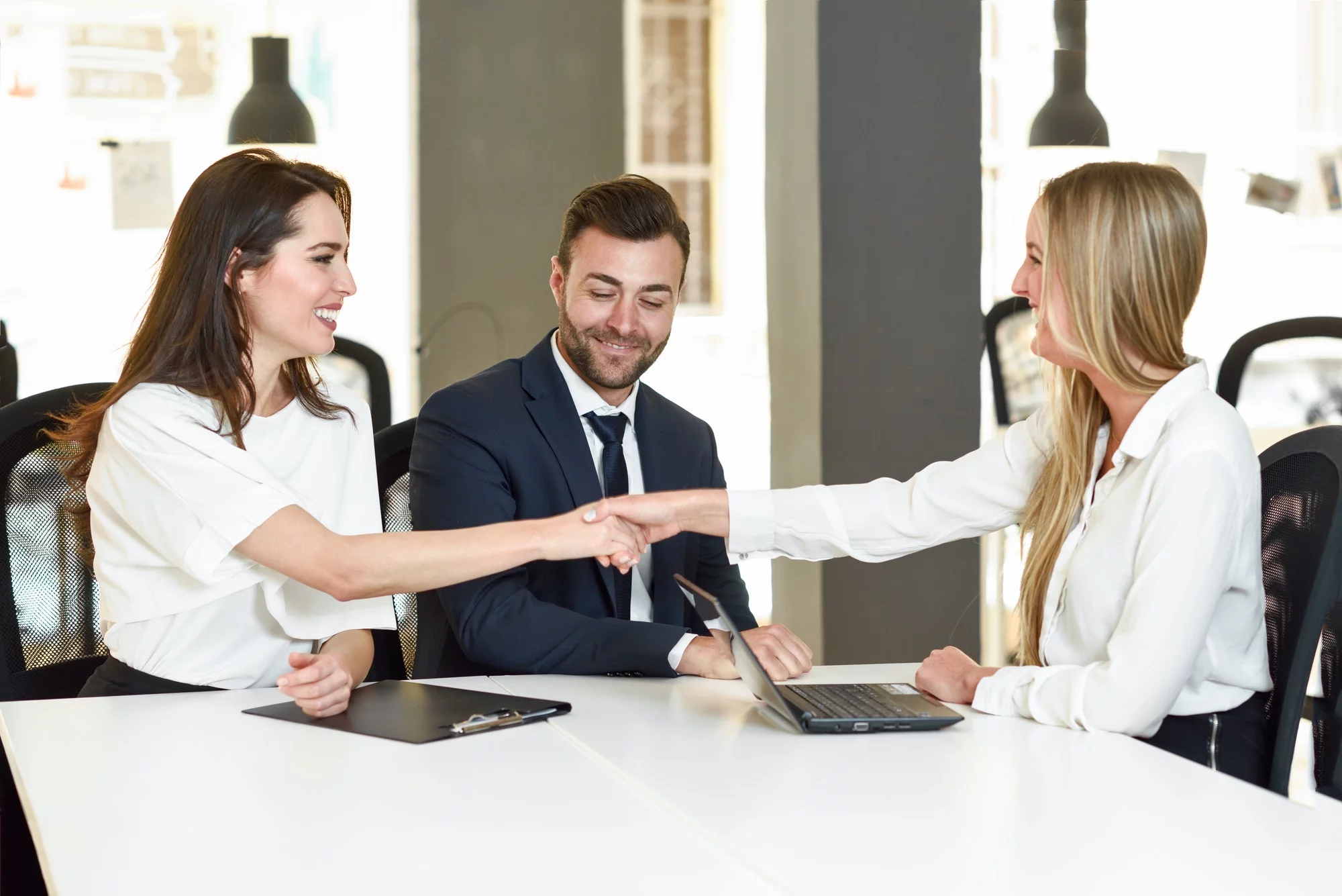 Smiling young couple shaking hands with an insurance agent