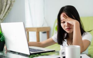 Stressed Asia woman work from home with computer at home - The present Global challenges impacting the future