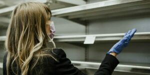 Woman with empty shelves in a supermarket during coronavirus - The present Global challenges impacting the future