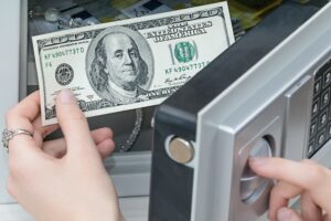 a woman's hand pulls out dollars from the safe