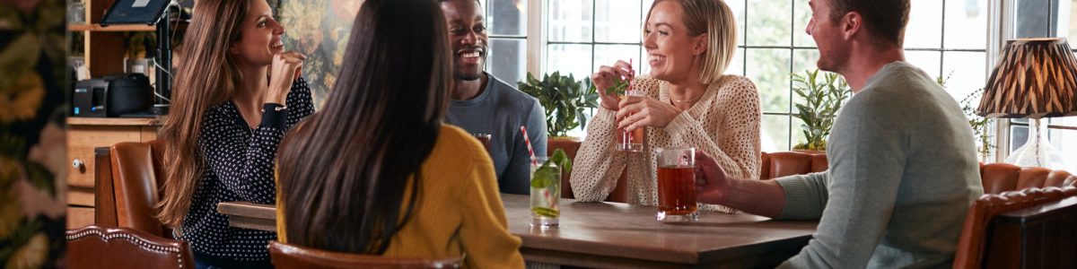 Group Of Friends Meeting For Lunchtime Drinks In Traditional English Pub