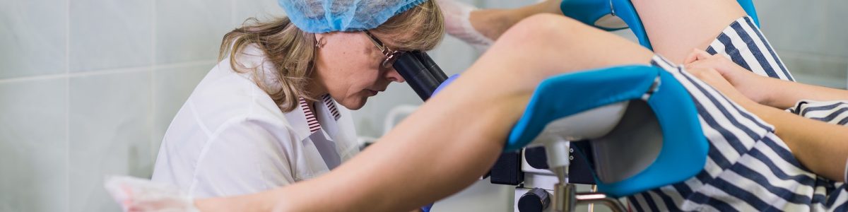 Senior female positively gynecologist examining a patient at clinic, health care concept